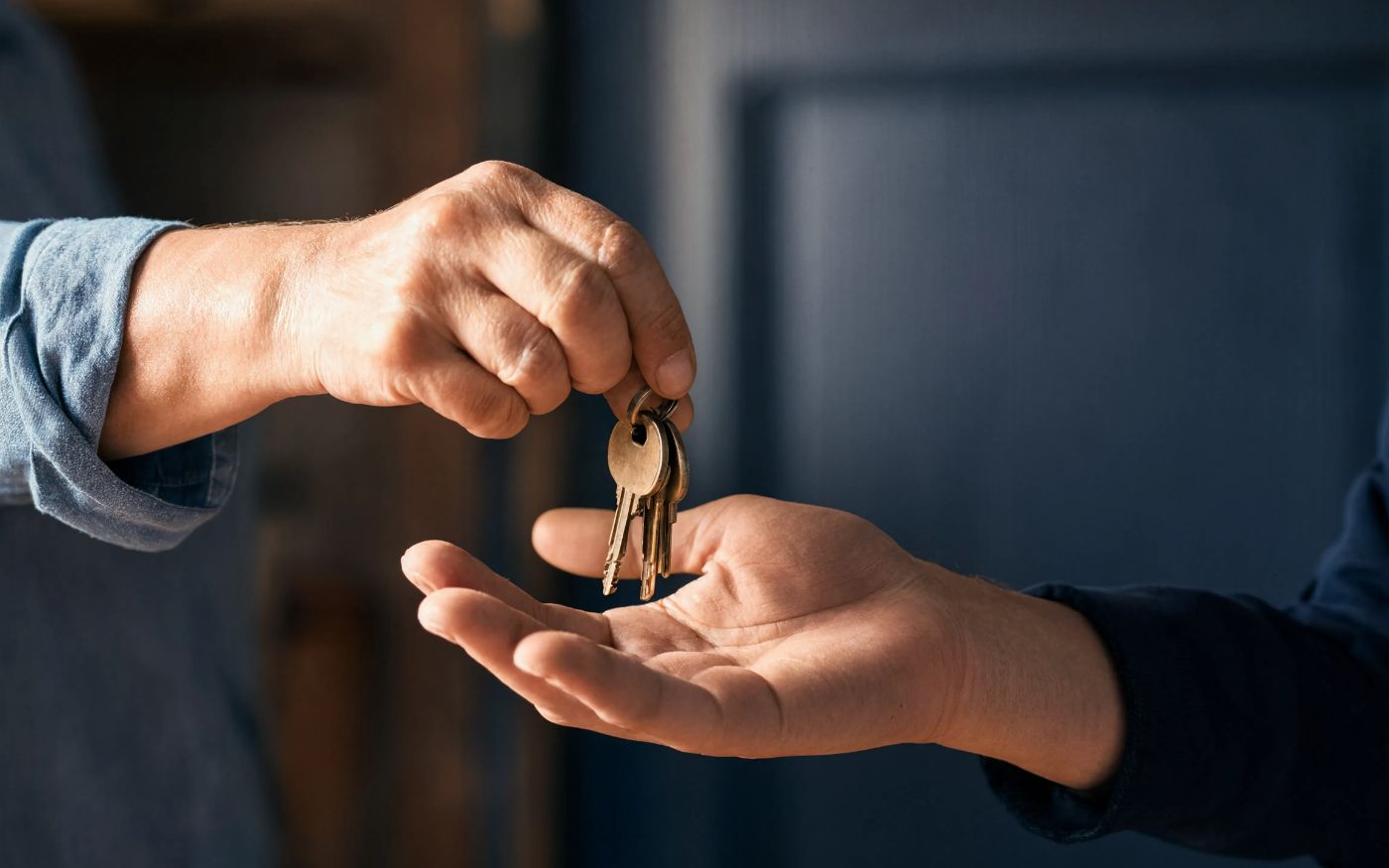 One person handing a ring of house keys into another person's open palm